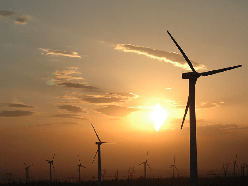 Wind turbines silhouetted against a vibrant sunset, harnessing renewable energy from the wind